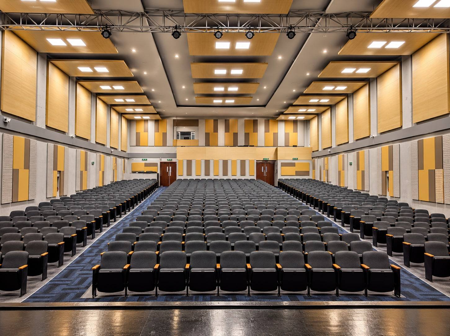 Auditorio con paneles acústicos en madera en muros y techo.
