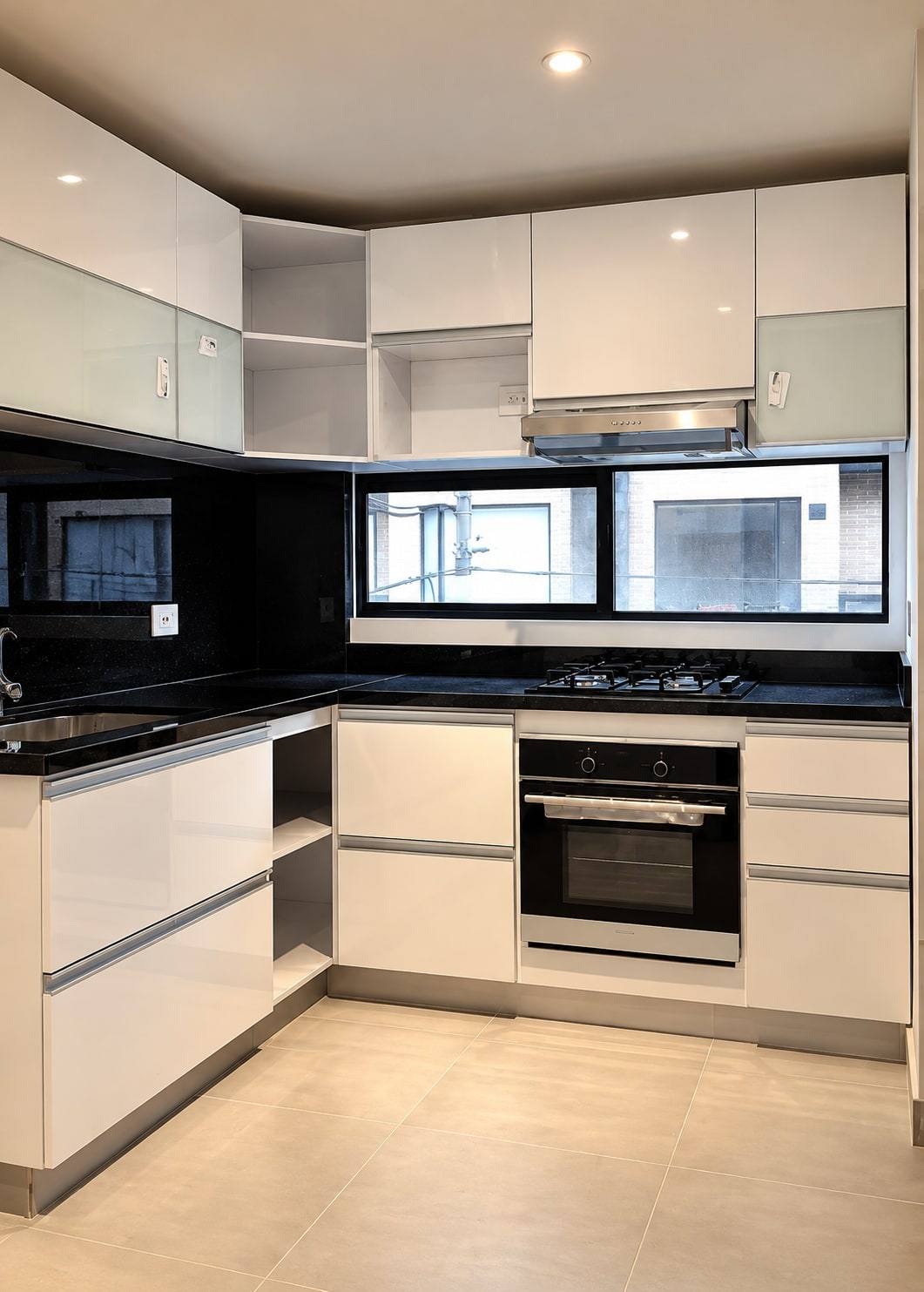 Cocina en L con muebles blancos, mesón negro y horno empotrado.