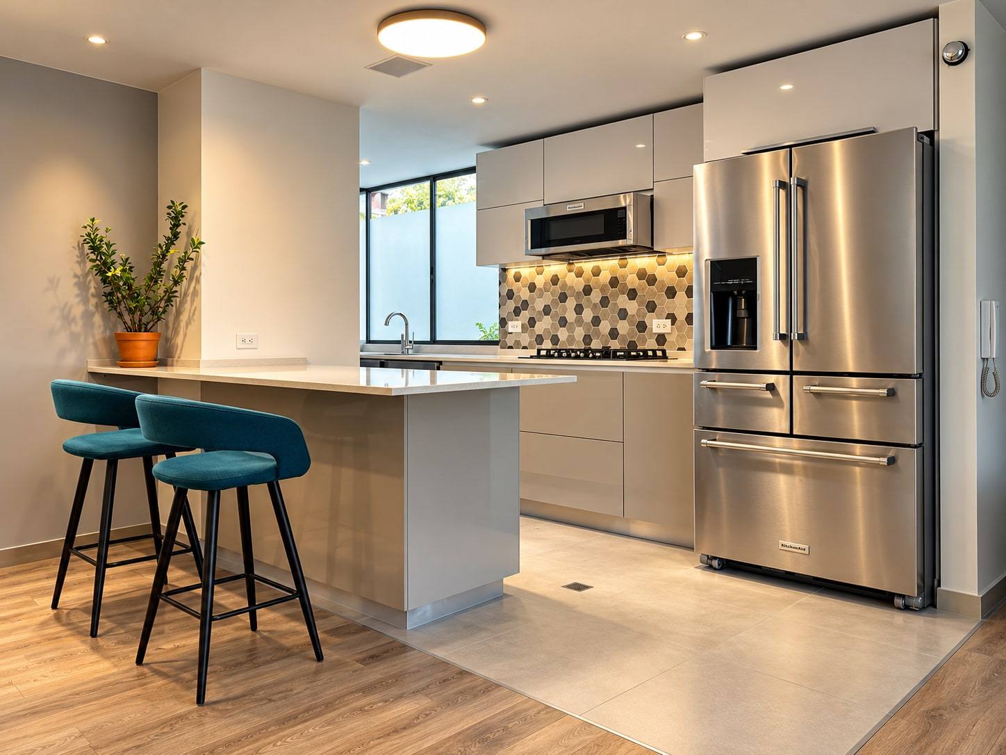 Cocina con isla gris, barra con taburetes y muebles altos claros.