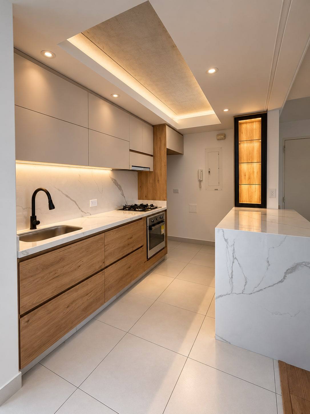 Cocina con muebles bajos en madera, muebles altos claros e isla con mesón tipo mármol.