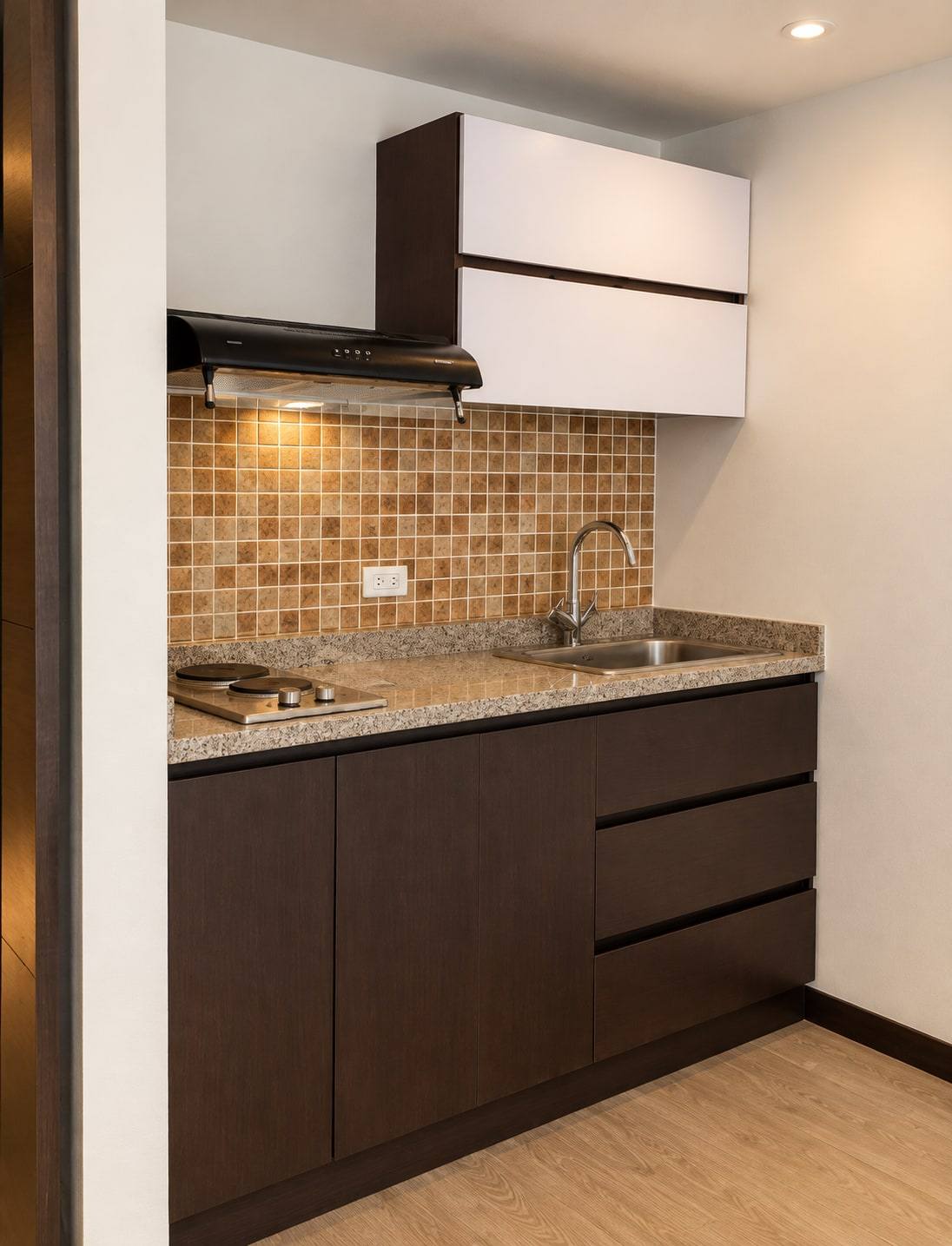 Cocineta con muebles oscuros, mueble alto blanco y enchape de mosaico.