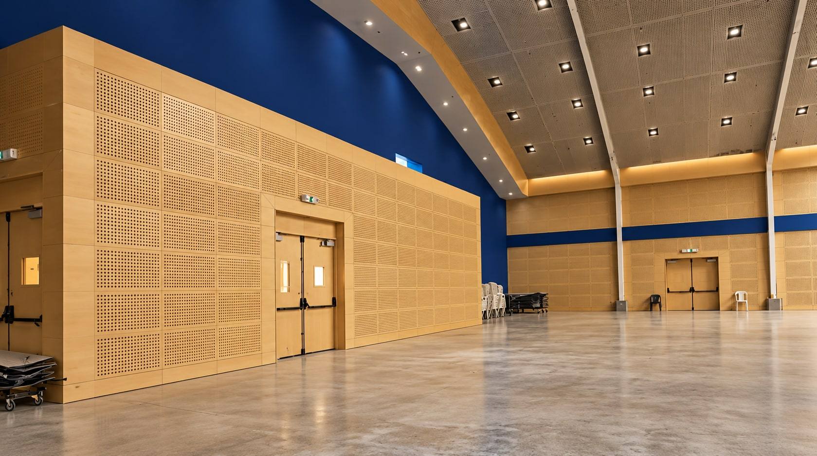 Muro acústico de madera perforada en un salón amplio.